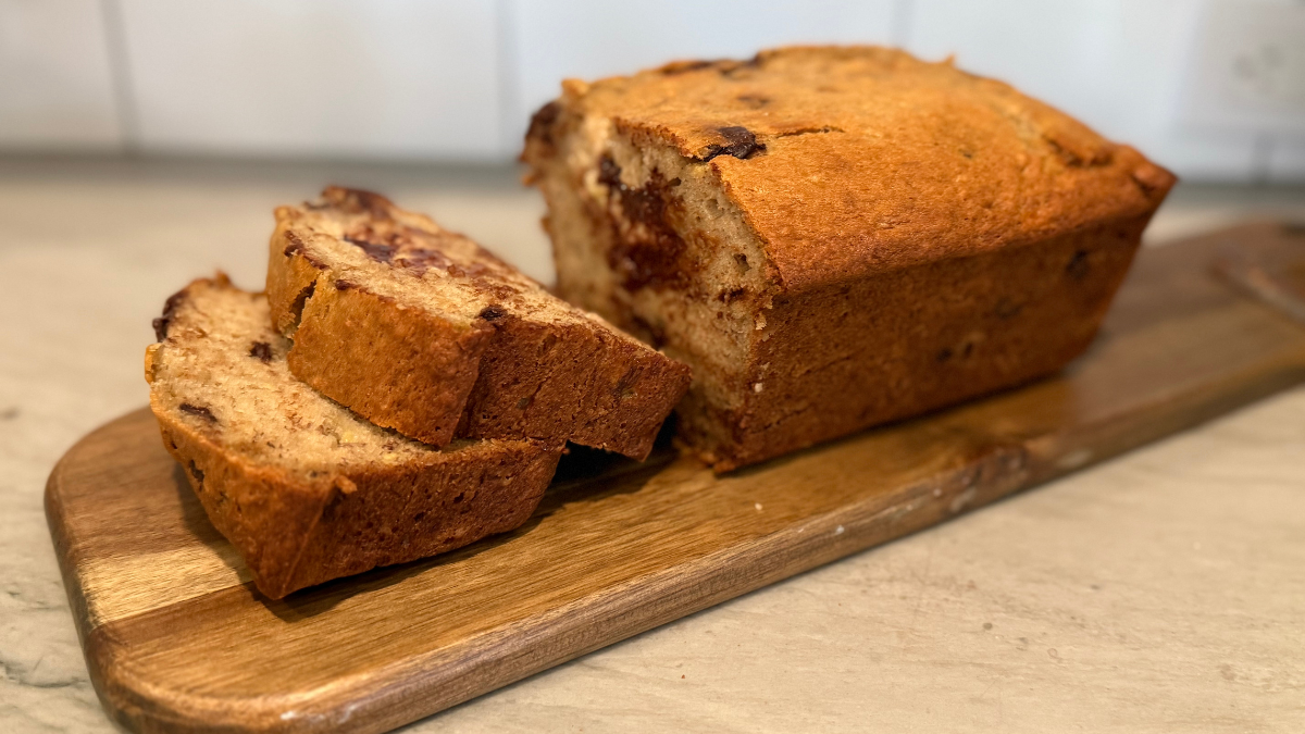 Moist banana chocolate chip bread sliced on wooden board.